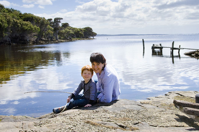 Serena and Riley sitting on a rock next to an inlet.